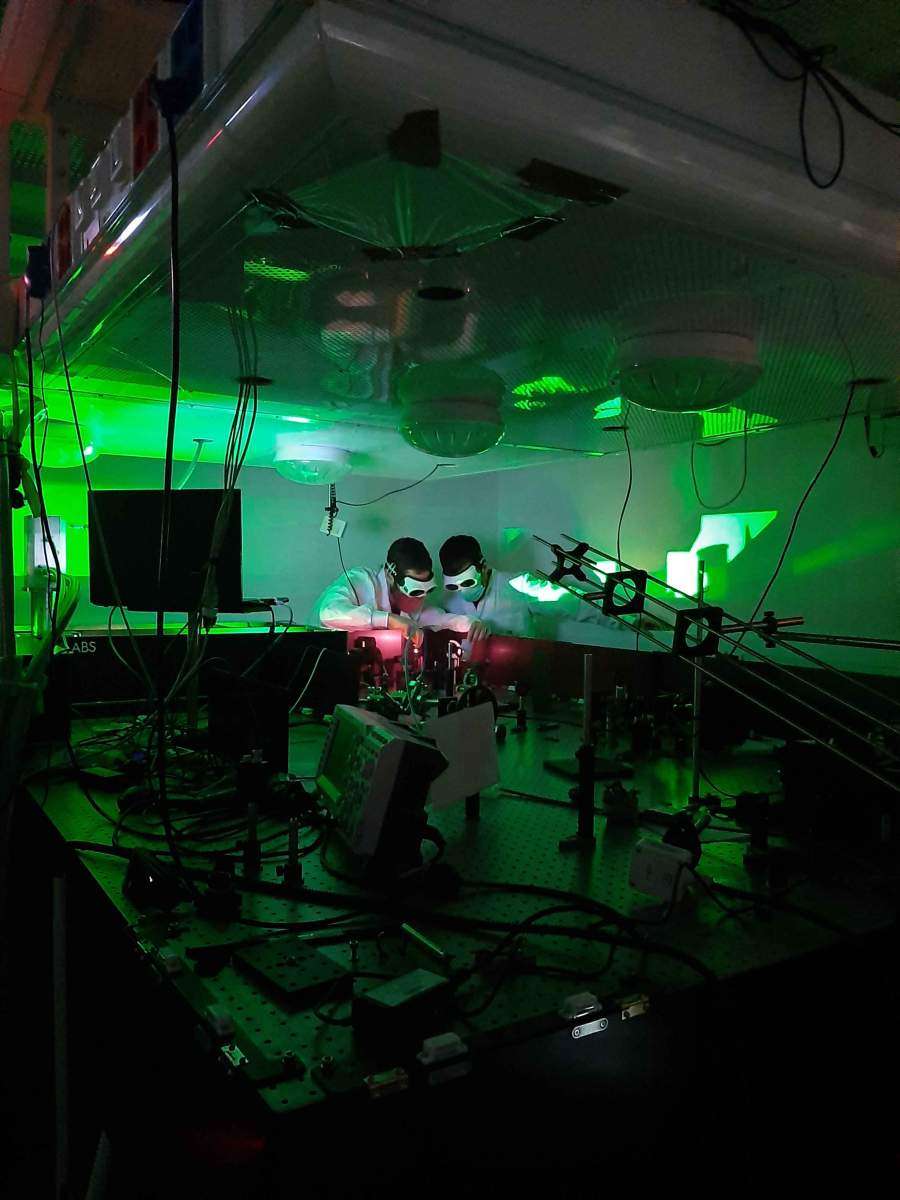 Le Dr Omer Kneller (à gauche) et Chen Mor dirigent un faisceau laser avant qu'il n'entre dans le dispositif expérimental. L'expérience nécessitait un faisceau laser puissant capable de produire des impulsions lumineuses d'une durée exceptionnellement courte, de l'ordre de l'attoseconde. Photo : Noa Yaffe 